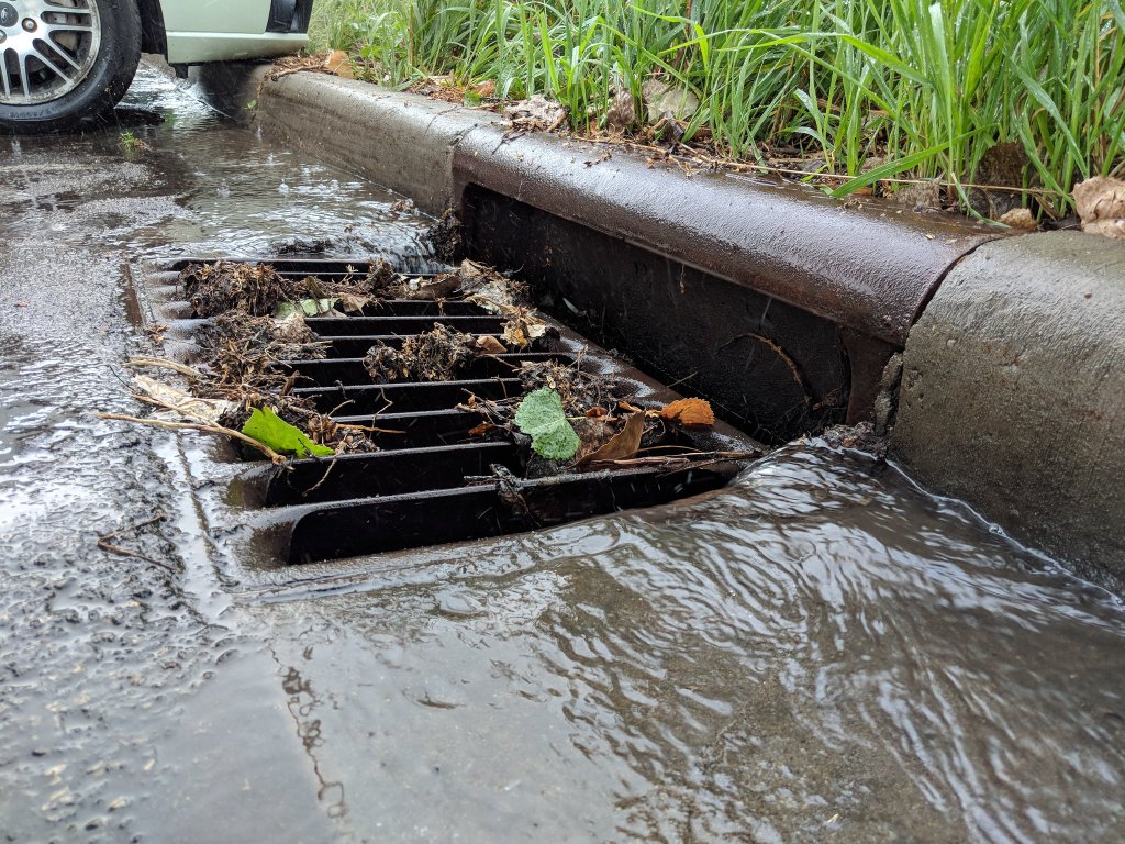 Photo of a storm drain with water flowing into it.